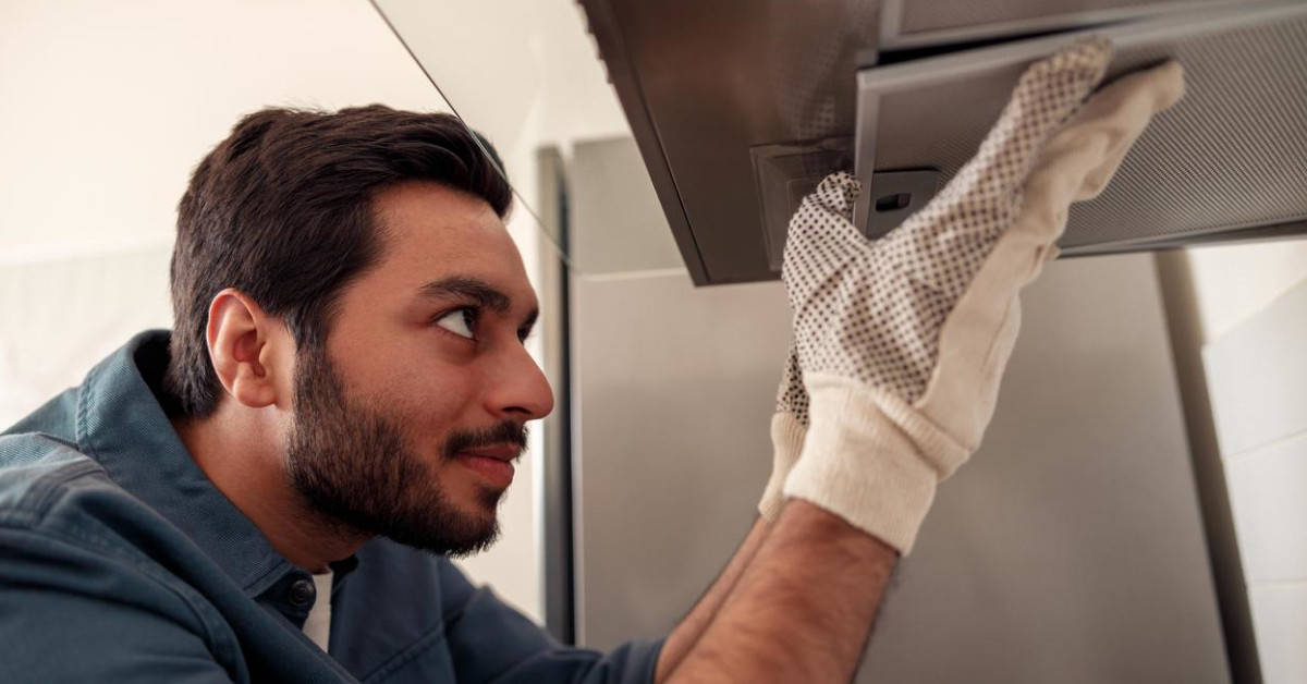 A professional technician cleans a commercial exhaust hood.