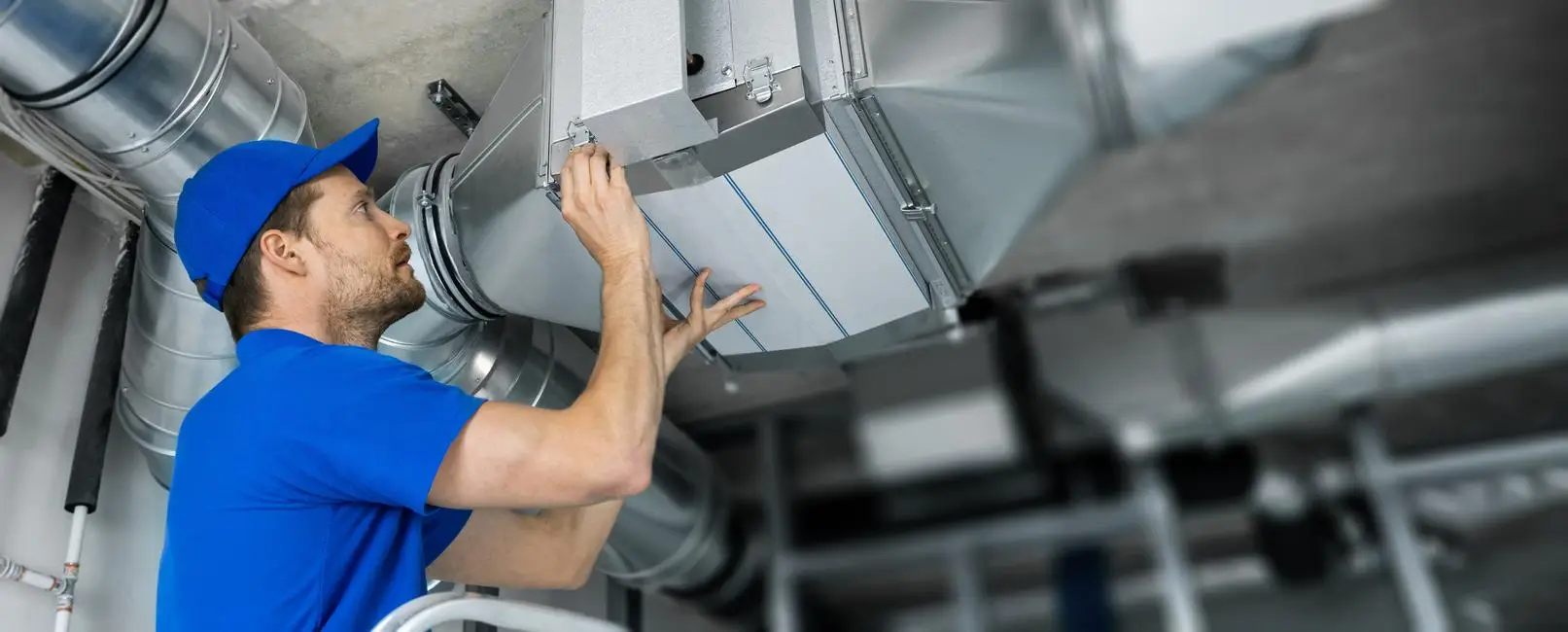 Technician installing a commercial kitchen exhaust ventilation system