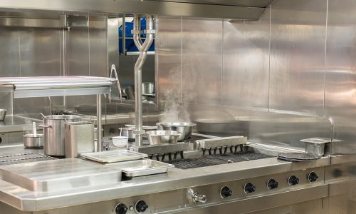 Food Being Cooked In Commercial Stainless Steel Kitchen In Resta Stainless steel wall panels and custom prep tables maximize cleanliness and efficiency, helping small commercial kitchens optimize space and workflow.
